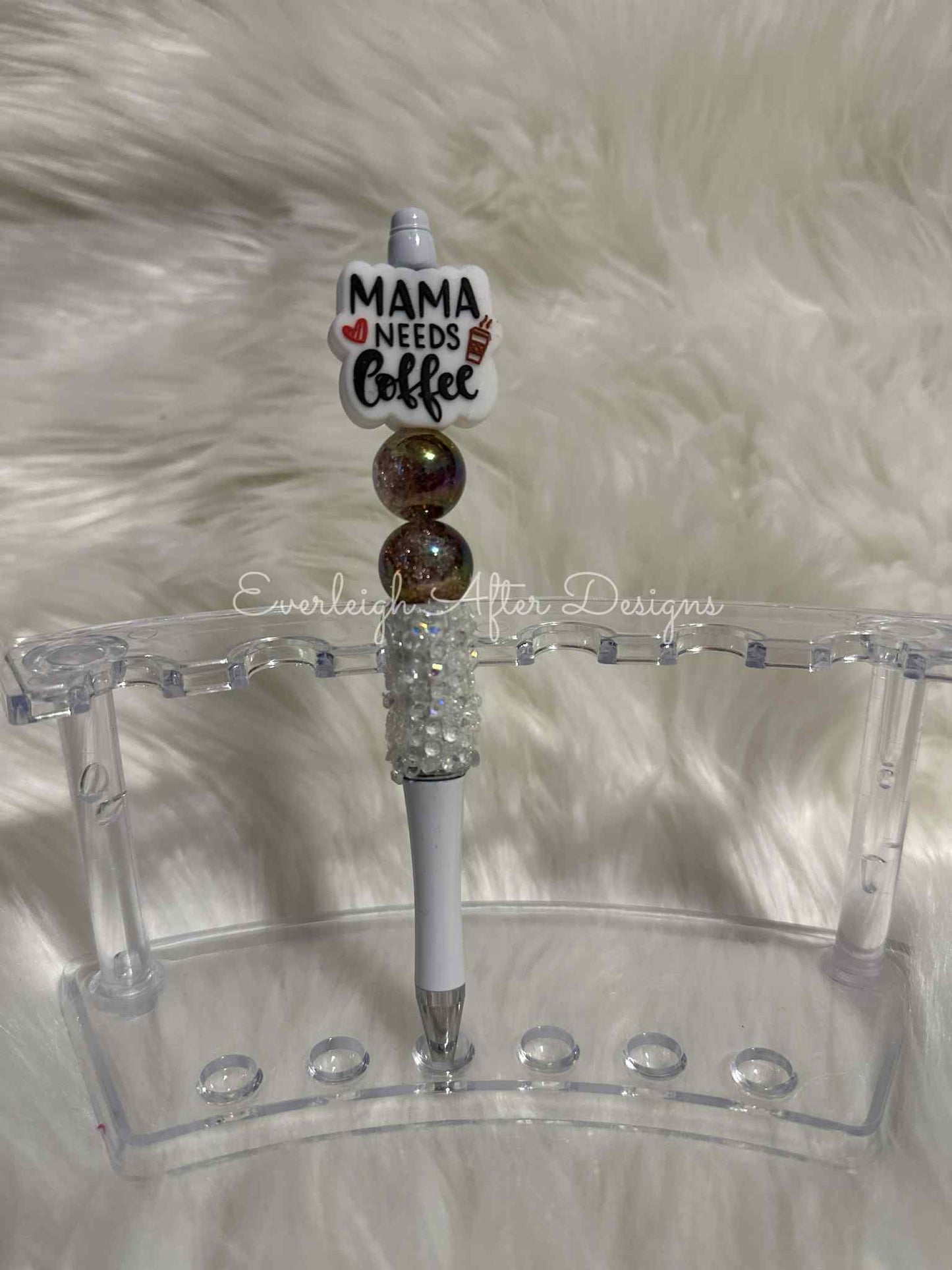 Decorative pen with 'Mama Needs Coffee' holder on a white fur background