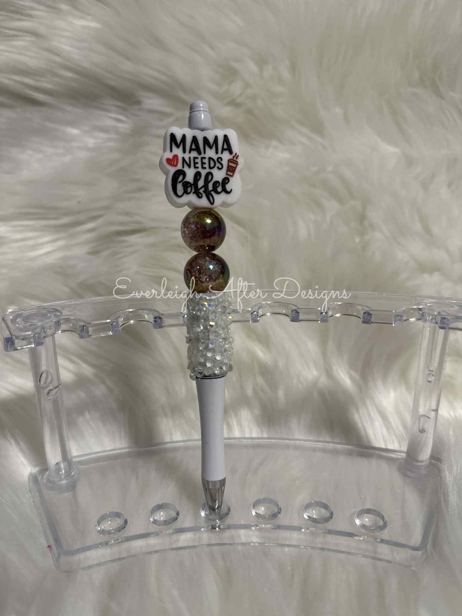 Decorative pen with 'Mama Needs Coffee' holder on a white fur background
