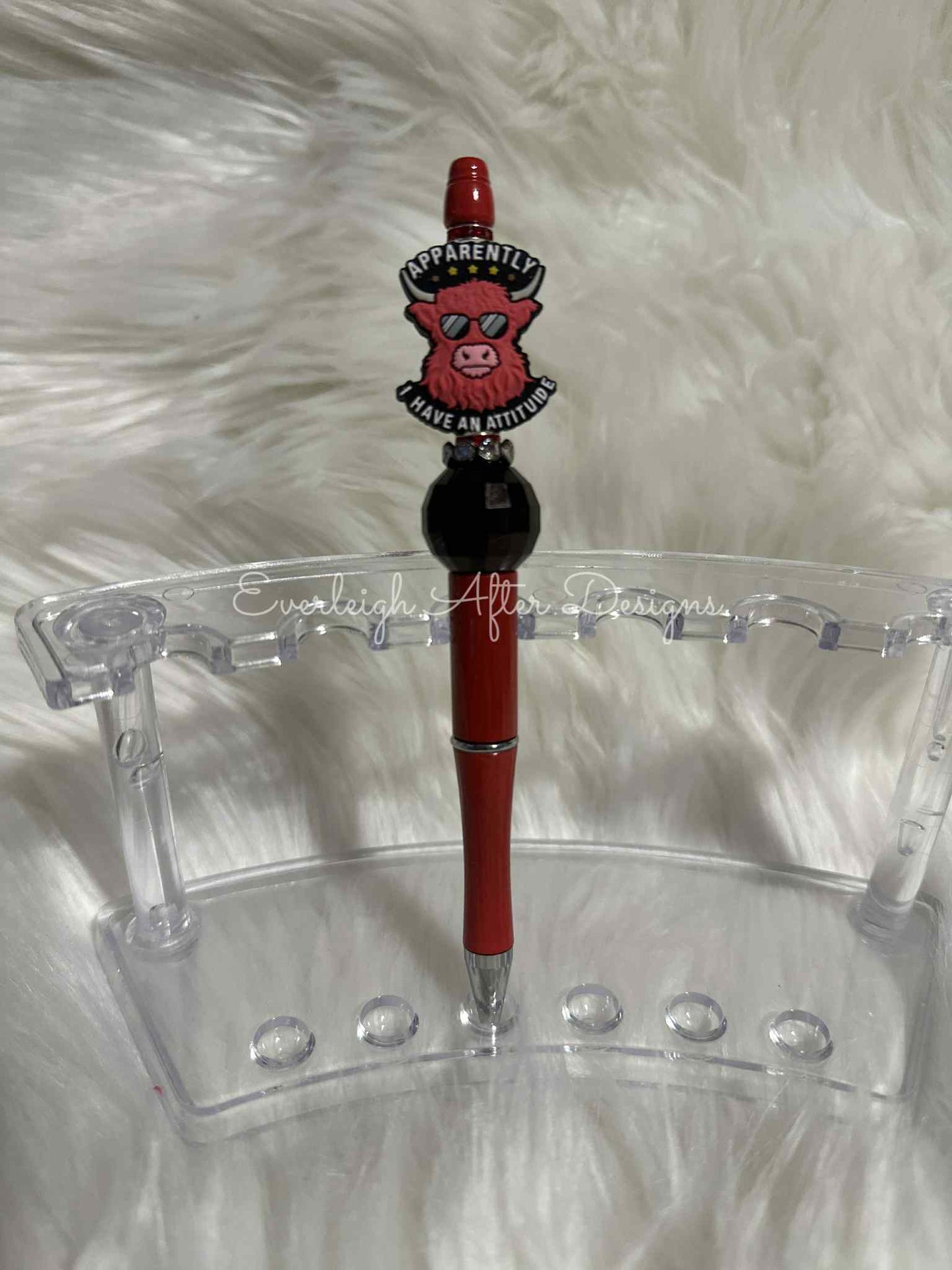 Red pen with a decorative top on a clear stand against a white fur background